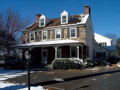Two-story brick senior living building with dormer windows and a snow-covered front porch.