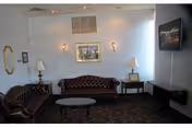Small sitting room with two tufted leather sofas, a coffee table, end tables with lamps, wall art, and a wall-mounted TV.