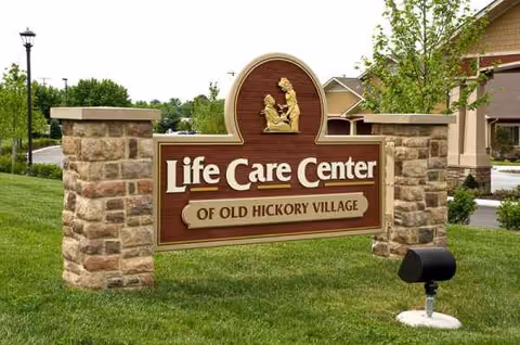 Exterior sign reads Life Care Center of Old Hickory Village with brick pillars and landscaping.
