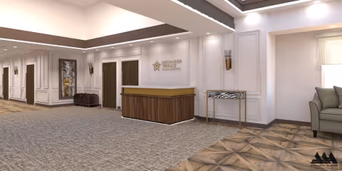 Interior view of a reception area in Birchwood Terrace Rehab and Healthcare featuring a wooden reception desk with a sign on the wall behind it, beige walls with decorative paneling, a patterned carpet, a small table with a zebra print top, and a green armchair near a window with blinds.