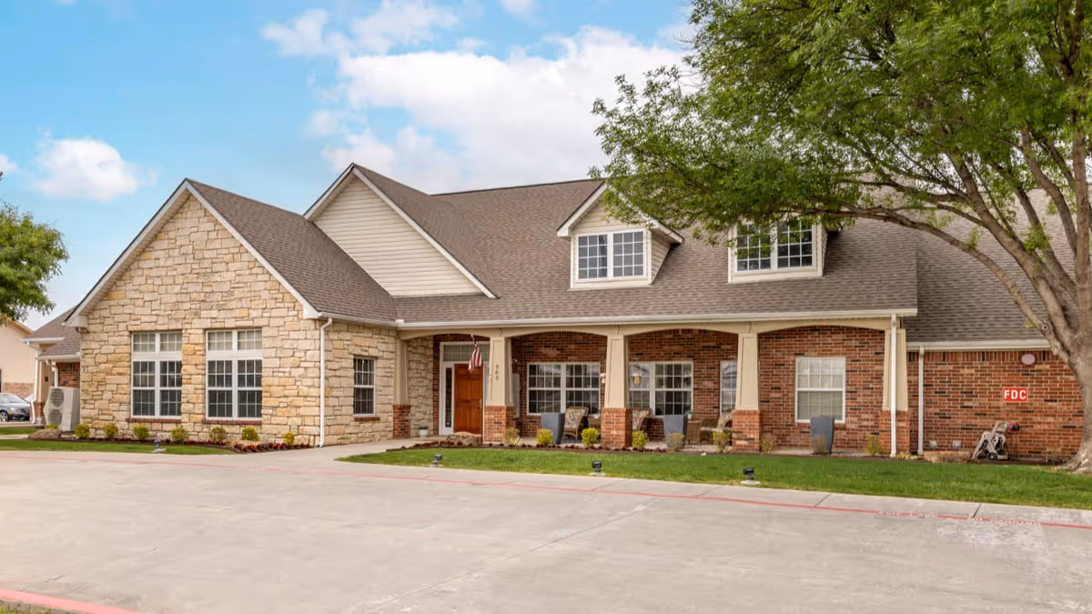 Single-story brick and stone building with a covered front porch, large windows, and surrounding landscaping.