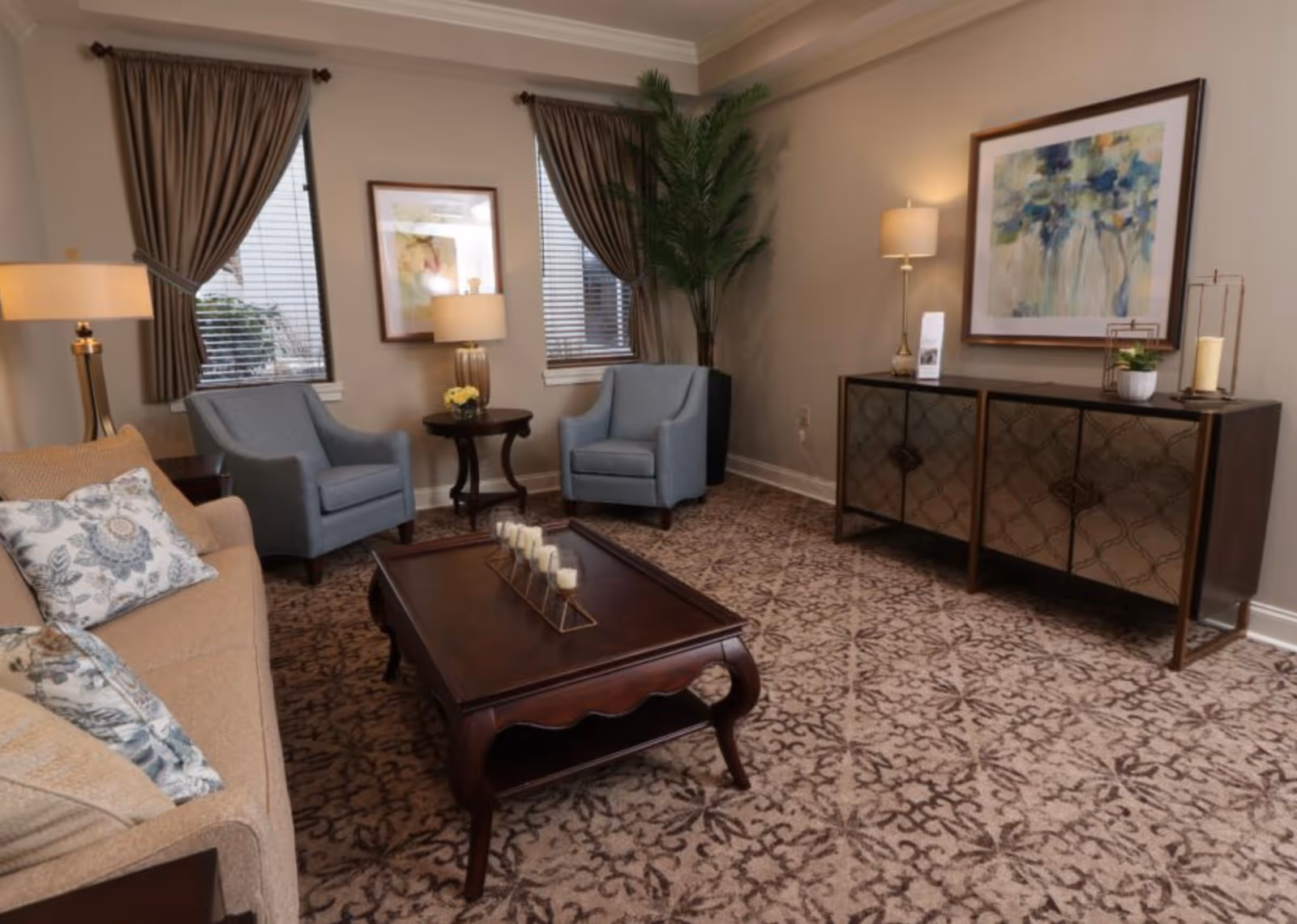 Cozy furnished sitting room with a sofa, two armchairs, coffee table, sideboard, lamps and framed artwork.