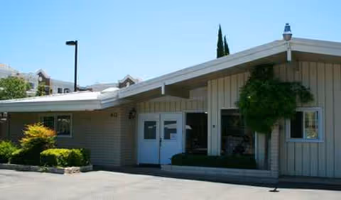 Exterior view of Pleasant Hill Oasis facility with a covered entrance and landscaped shrubs.