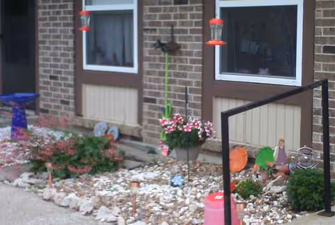 Exterior view of a brick senior apartment building with a small rock garden.