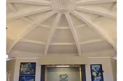 Interior view of a nursing and rehabilitation center lobby with a high, dome-shaped ceiling featuring exposed beams. The walls have framed artwork and a sign with the facility's logo and name, Mitchell-Hollingsworth Nursing & Rehabilitation Center.