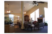 Bright common living room with comfortable seating, a fireplace, ceiling fans, and large windows.