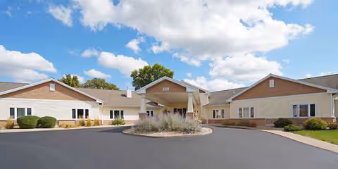 Wide view of Park Place Assisted Living building exterior with circular driveway and landscaped entrance.