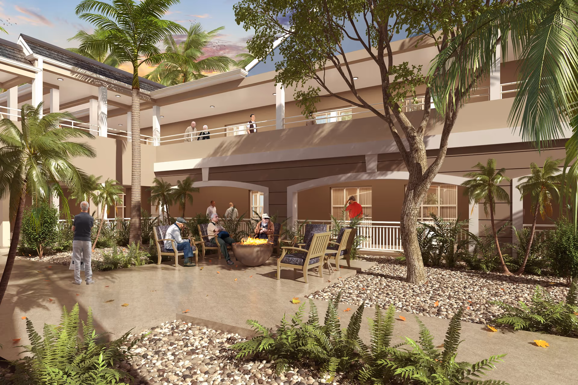 Outdoor courtyard area at Discovery Village At Boynton Beach featuring several elderly people sitting around a fire pit with chairs, surrounded by palm trees and other greenery. The courtyard is enclosed by a two-story building with balconies and railings, and a few people are seen standing and walking on the upper level.