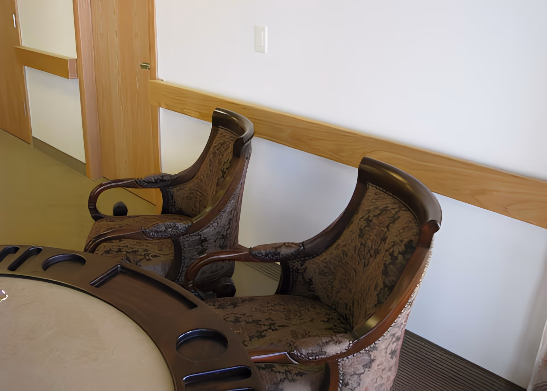 Two upholstered armchairs beside a round table in a hallway sitting area.
