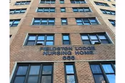 Brick nursing home building facade with many windows and a sign near the top.