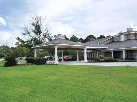 Exterior view of a senior living facility with a covered entrance and manicured lawn.