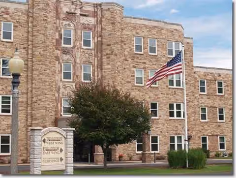 Brick three-story building with American flag and Bell Tower Residence Assisted Living sign.