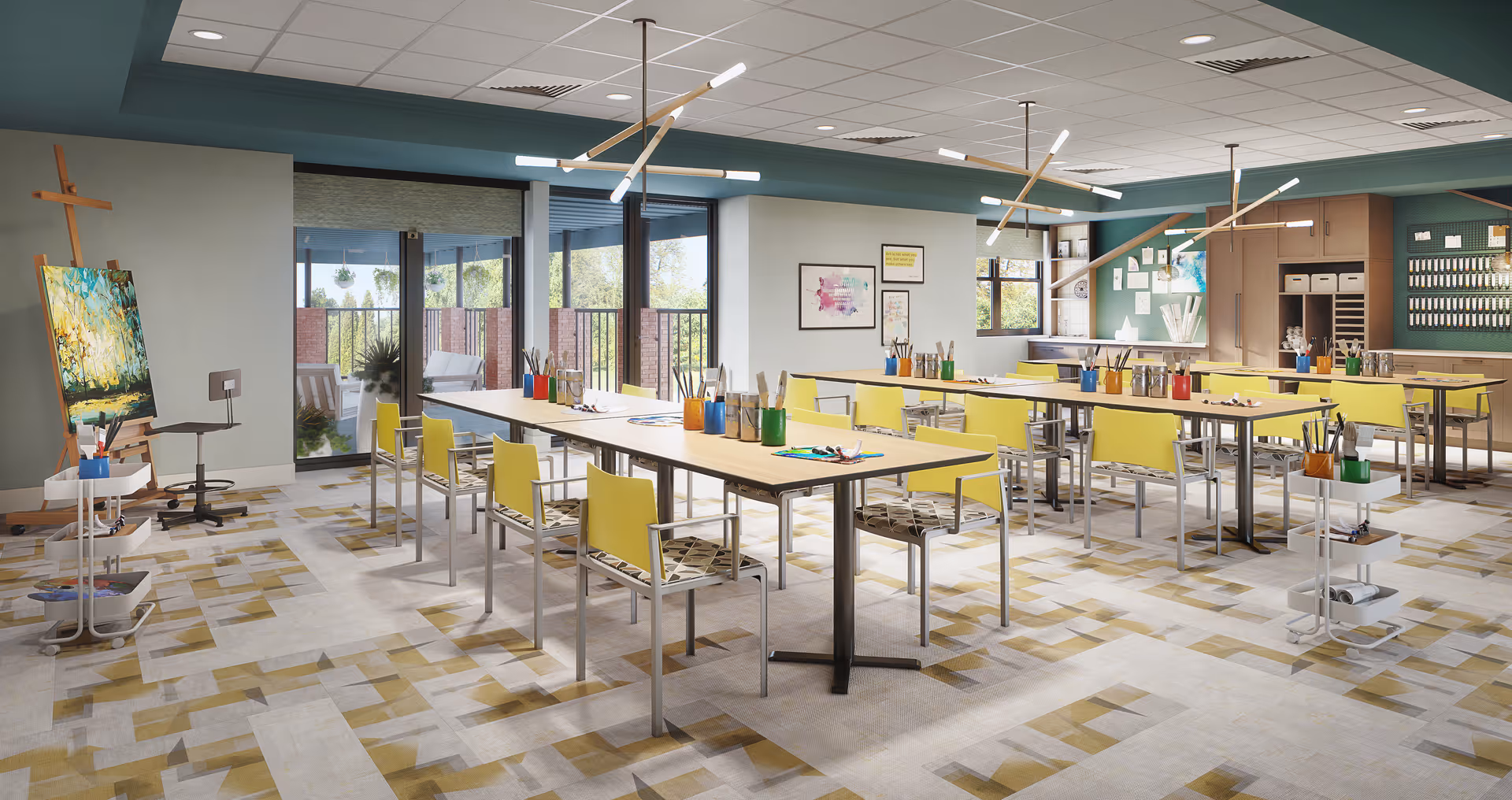 Bright communal art and activity room with long tables, yellow chairs, easels, and art supplies, opening onto a sunlit patio.