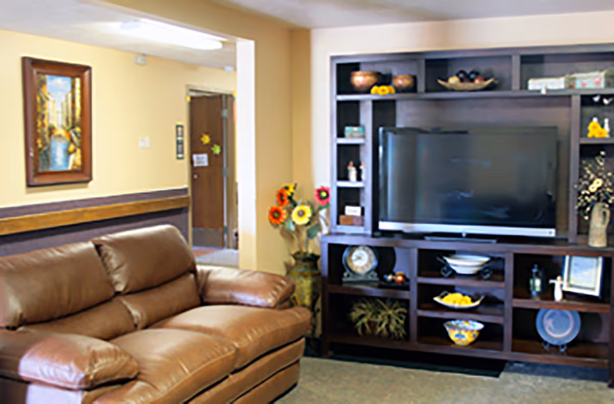 Living room with a brown leather sofa facing a large dark wood entertainment center holding a flat-screen TV and decorative items.