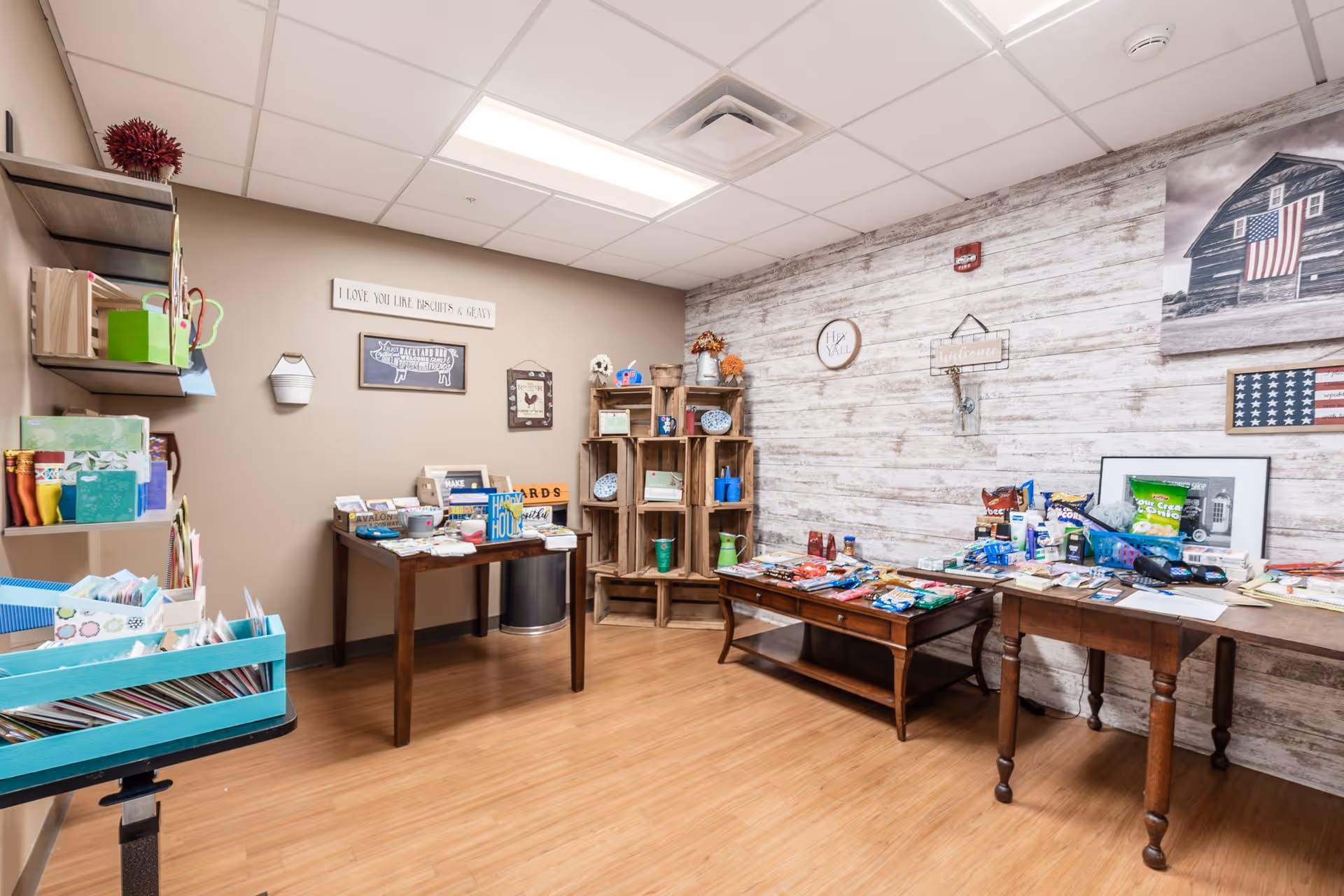 Bright activity/craft room with tables and shelves displaying snacks, supplies, and decor against a wood-paneled wall.