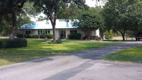 Exterior view of a single-story facility with a blue roof and green lawn.