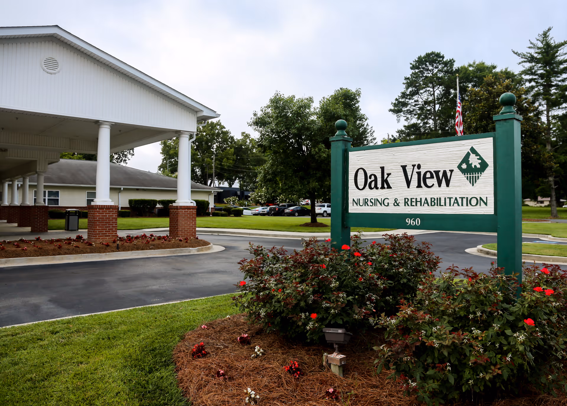 Front entrance and sign reading 'Oak View Nursing & Rehabilitation' beside a circular driveway and landscaped beds at a one-story facility.