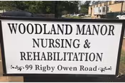 Exterior sign reads Woodland Manor Nursing & Rehabilitation in front of a building.