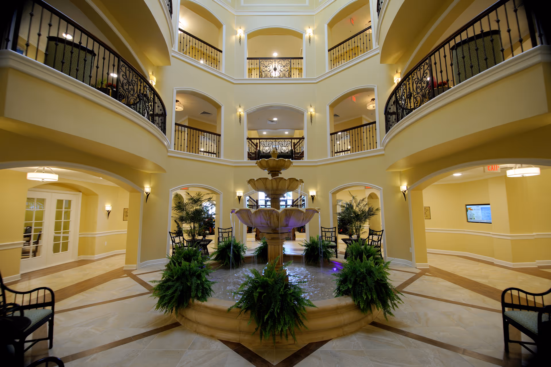 Spacious multi-level indoor atrium with a central fountain, seating areas, plants, and ornate balconies.