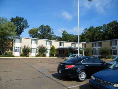 Exterior view of Attala County Nursing Center showing a two-story building, parking lot, and trees.