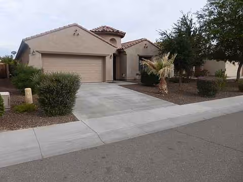 Front view of a single-story tan assisted living home with a driveway and desert landscaping.