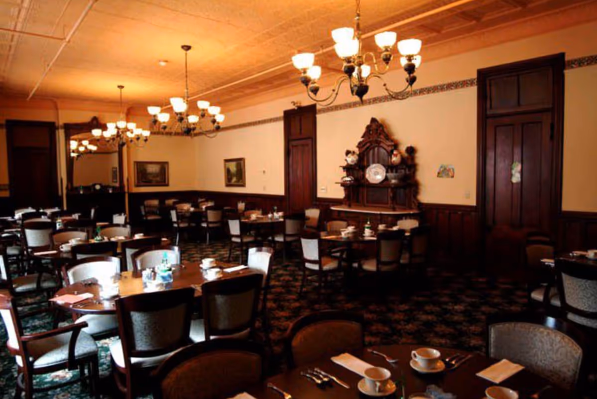 An elegantly furnished dining room with tables set for meals in a senior living facility.