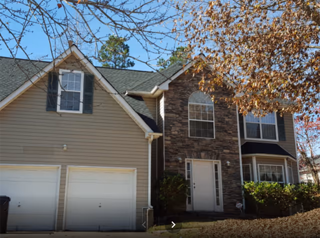 Front view of a two-story house-style facility with stone facade and attached garage.