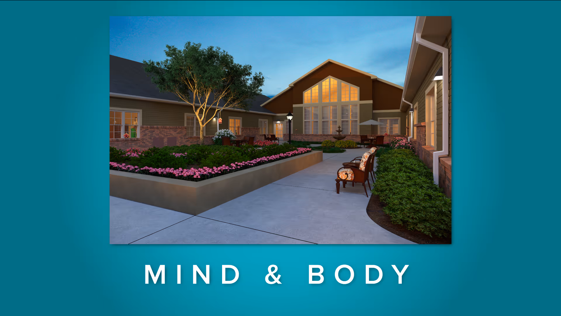 Outdoor courtyard area at dusk with a paved walkway, garden beds filled with pink flowers and green shrubs, several chairs with cushions along the path, and a building with large windows illuminated from inside.