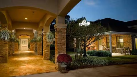 Evening exterior of Atria Copeland with covered walkway and lit entrance
