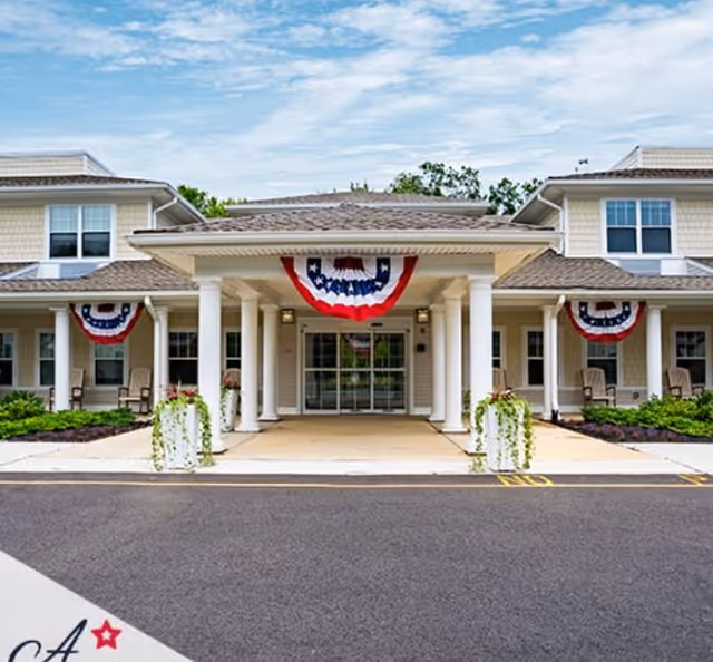 Front entrance of a senior living building decorated with red, white, and blue bunting.