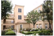 Beige multi-story senior living building with a landscaped courtyard and trees.
