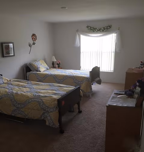 Two single beds with matching quilts, a dresser, and a window in a tidy bedroom.