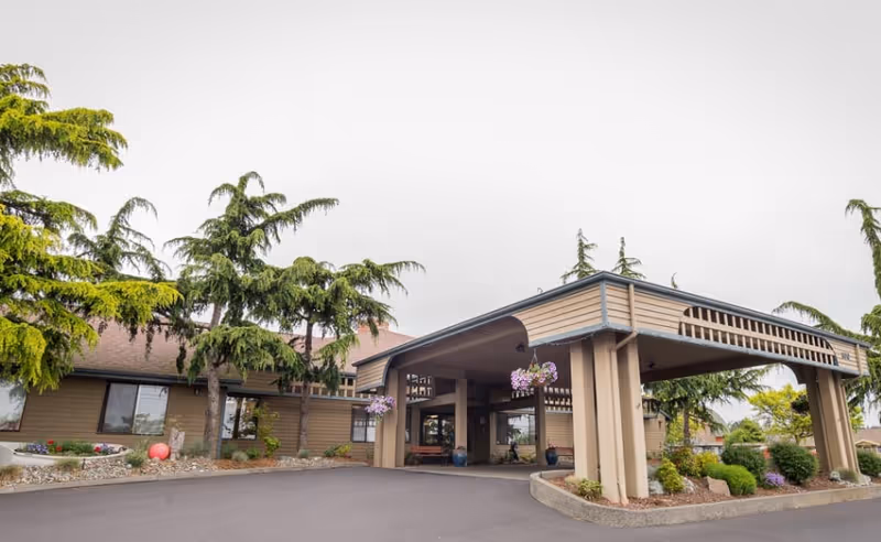 Front exterior of a senior living facility with a covered entrance and landscaping.