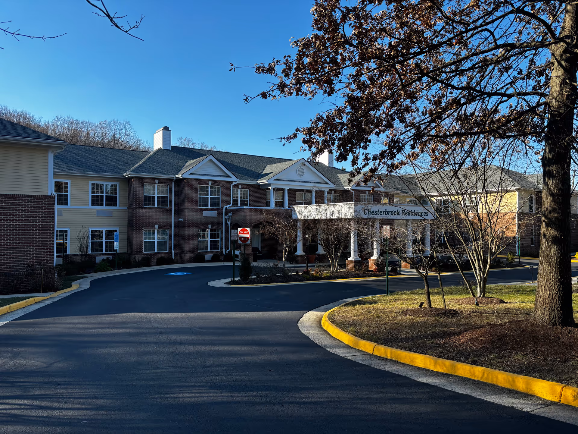 Front exterior of Chesterbrook Residences senior living building with a covered entrance and circular driveway.