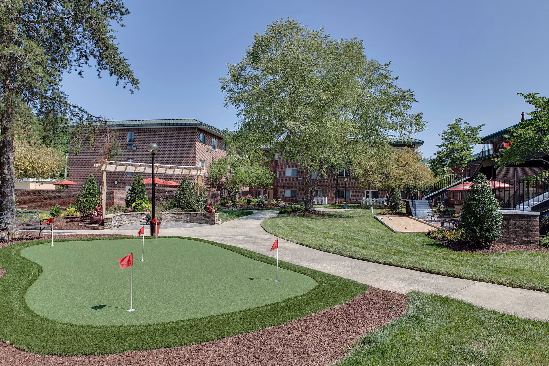 Courtyard of Bartlett Reserve with a small putting green, walking paths, trees, and surrounding brick buildings.