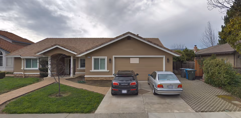 Front view of a single-story care home with a two-car driveway and parked cars.