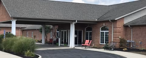 Brick exterior of an assisted living facility with a covered entrance and seating.