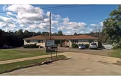 Exterior view of Rebecca's Personal Care Home Inc., a single-story facility with a sign and cars.