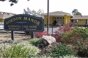 Gordon Manor sign in front of a yellow residential care building with landscaping