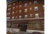 Front facade of Hotel Pennsylvania Apartments, a brick building with glass storefront and lit entrance canopy.