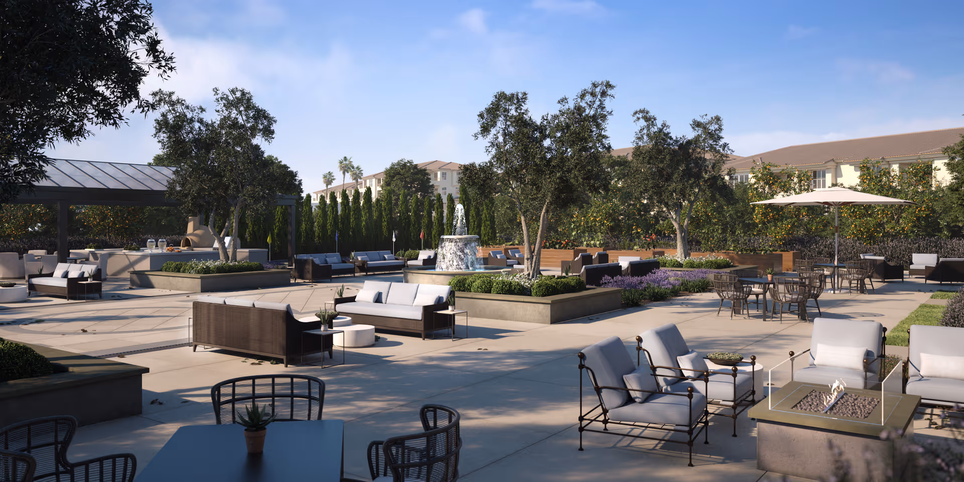 Sunlit outdoor courtyard with multiple seating areas, tables, planters, and a central fountain.