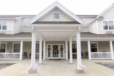 Front entrance of a senior living facility with white columns and double doors.