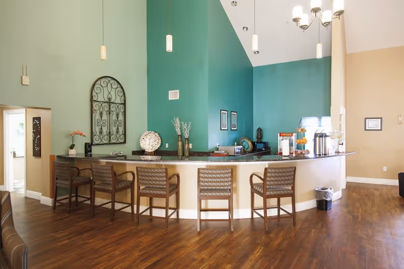 Interior common area with a curved service counter and several bar stools in front of a teal accent wall.