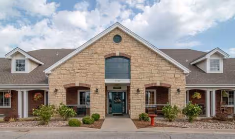 Front view of Waldron Place senior living facility with stone facade and entrance walkway.