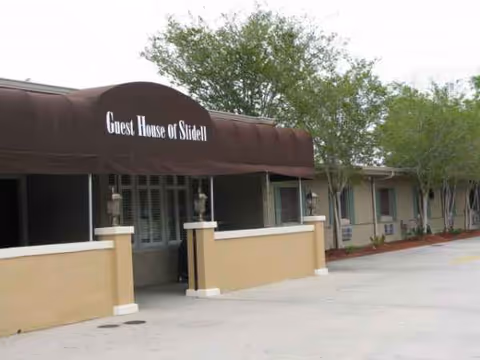 Front entrance of Guest House of Slidell with a brown awning and exterior walls.