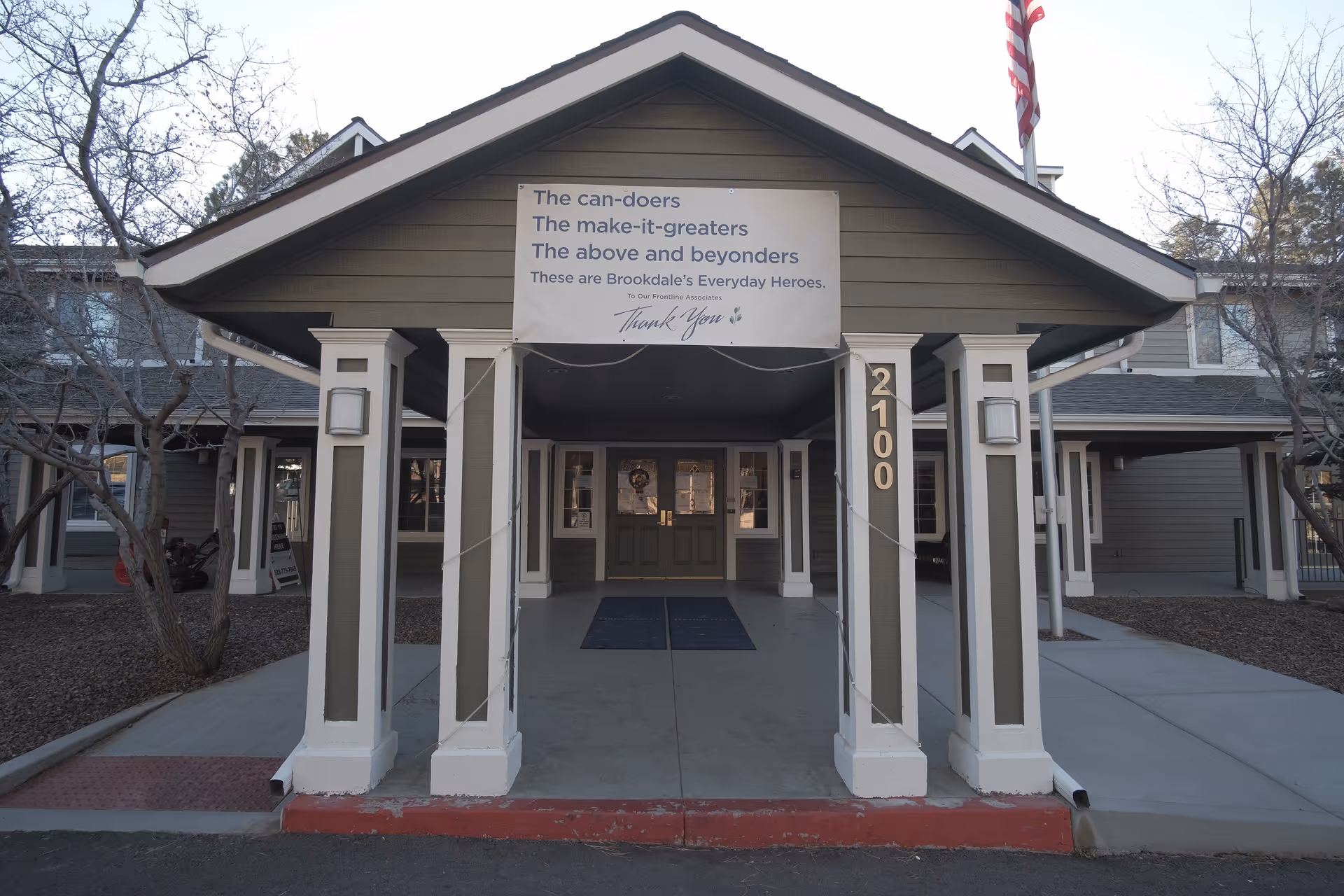 Covered entrance and porte-cochere of Brookdale Flagstaff with columns, address number 2100, and a banner above the doorway.