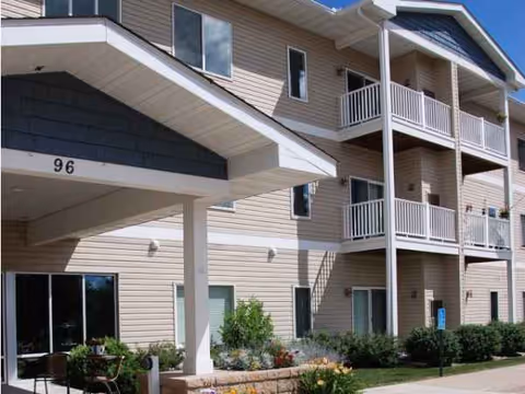 Exterior view of Pine Manor Estates senior living building with balconies and landscaped entrance
