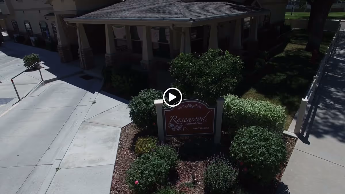 Front entrance of Rosewood Assisted Care with a landscaped sign, walkway, and building façade.