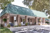 Brick facility front with green metal roof, columns, and a covered entrance.