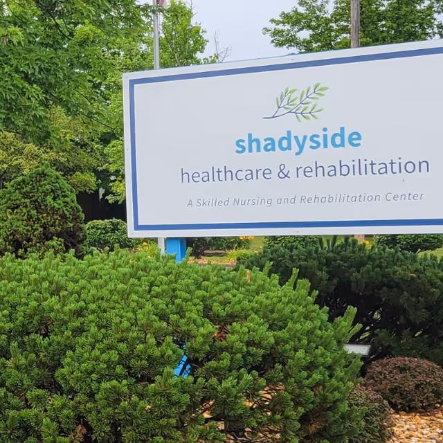 Outdoor sign reading "shadyside healthcare & rehabilitation" surrounded by shrubs and trees.